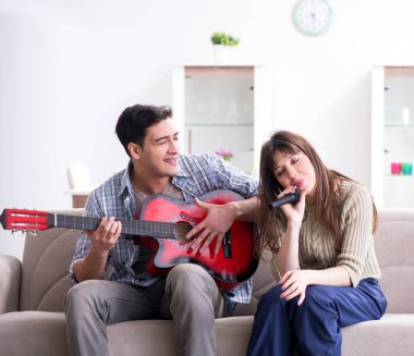 Genç bir aile evde şarkı söylüyor ve müzik çalıyor.