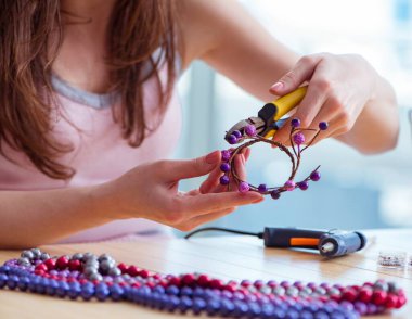 Kadın evde mücevher yapıyor.