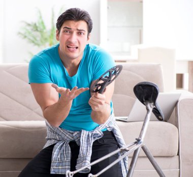 Evde bisiklet tamir eden genç bir adam.