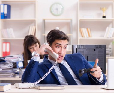 Meslektaşı meşgulken ofiste oyun oynayan adam.