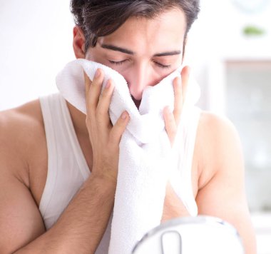 Genç yakışıklı adam aynaya bakıyor.