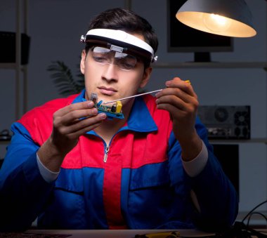 Bilgisayar uzmanı gece geç saatlerde bilgisayarı tamir ediyor.