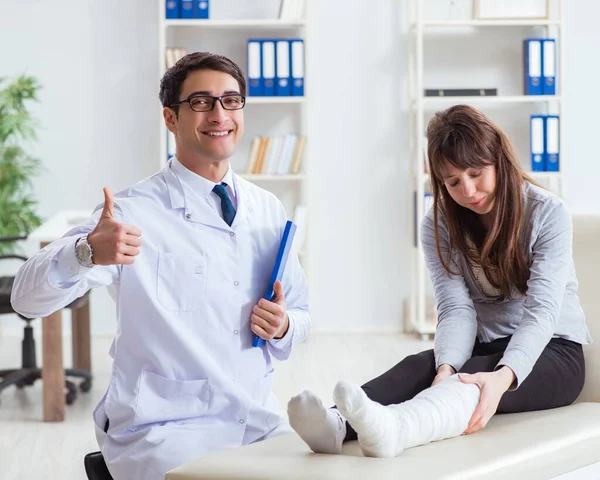 Medico esaminando paziente con gamba rotta — Foto Stock