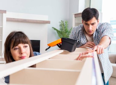 Yeni evde mobilya montajı yapan genç bir aile.