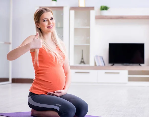 妊娠中の女性が家で運動をする — ストック写真