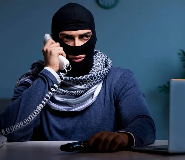 Terrorverdächtiger Einbrecher mit Waffe arbeitet am Computer — Stockfoto