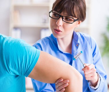 Doktor çekiçle sinir reflekslerini kontrol ediyor