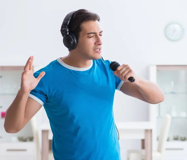 Jovem homem bonito cantando karaoke em casa — Fotografia de Stock