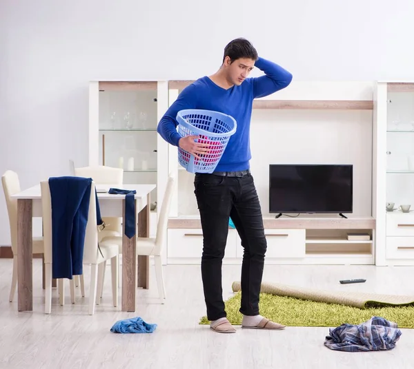 Jovem colecionando roupas sujas para lavanderia — Fotografia de Stock