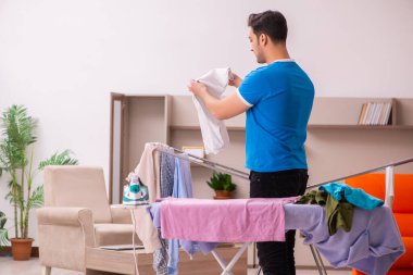 Genç adam evde ütü yapıyor.