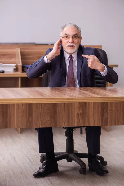 Старый бизнесмен сидит в офисе — стоковое фото