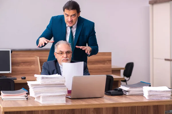 Vecchio datore di lavoro maschile e giovane assistente maschile nel concetto di bullismo — Foto Stock