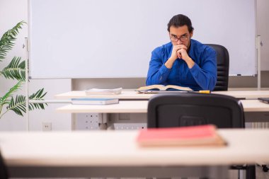 Genç erkek öğretmen beyaz tahtanın önünde.