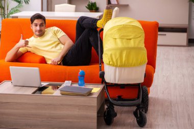 Genç adam evde yeni doğan çocuğa bakıyor.