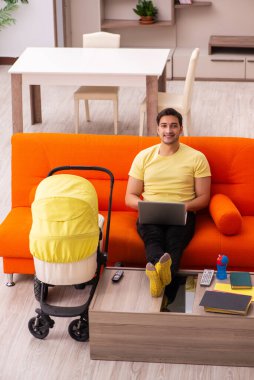 Genç adam evde yeni doğan çocuğa bakıyor.