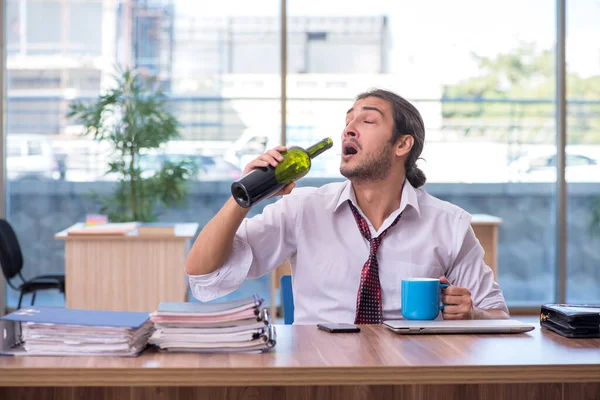 Jovem viciado em álcool masculino empregado que trabalha no escritório — Fotografia de Stock