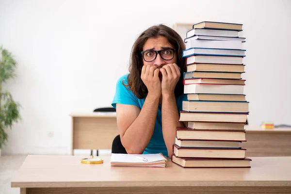 Jeune étudiant masculin et beaucoup de livres dans la classe — Photo