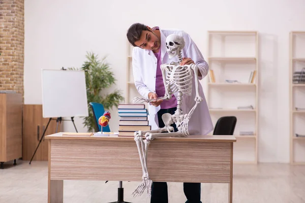 Joven estudiante de medicina que estudia esqueleto humano en el aula — Foto de Stock