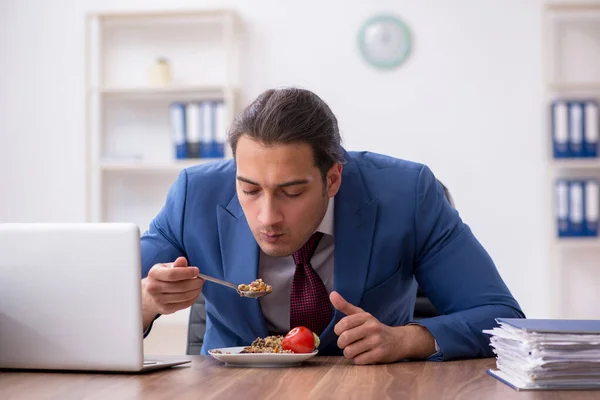 Hongerige mannelijke werknemer die boekweit eet tijdens de pauze — Stockfoto