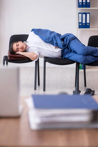Joven empleado masculino durmiendo en la oficina en sillas — Foto de Stock