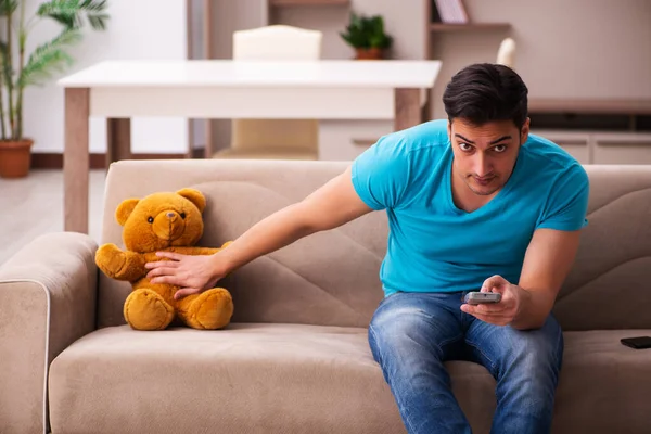 Jovem sentado com urso brinquedo em casa — Fotografia de Stock