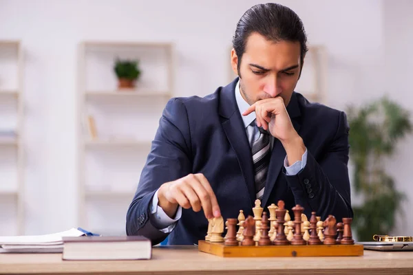 Joven empleado masculino jugando ajedrez en el lugar de trabajo — Foto de Stock