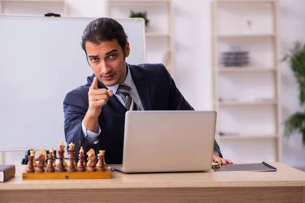 Joven empleado masculino jugando ajedrez en el lugar de trabajo — Foto de Stock