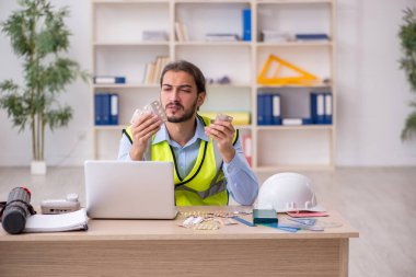 Genç erkek mimar işyerinde acı çekiyor.