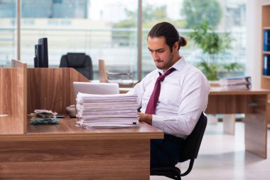 Genç bir erkek işçi ve ofiste çok fazla iş var.