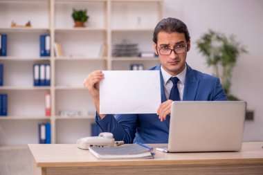 Genç erkek çalışan ofiste oturuyor.