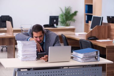 Ofisteki aşırı işten memnun olmayan genç bir erkek işçi.