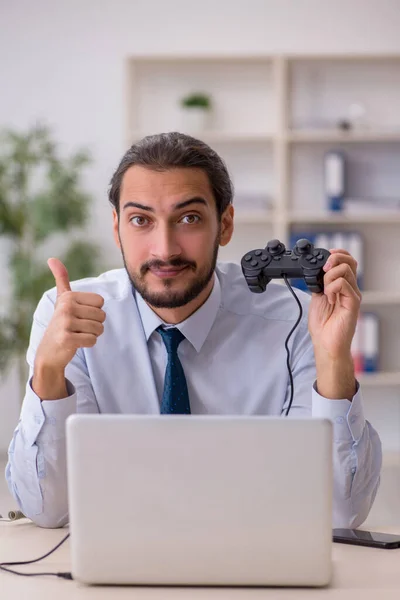 Jovem funcionário do sexo masculino jogando joystick jogos durante a sua pausa — Fotografia de Stock