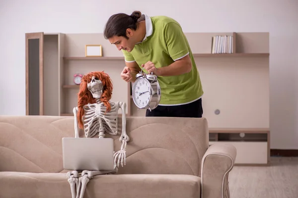Jovem com esqueleto feminino no conceito de gerenciamento de tempo — Fotografia de Stock