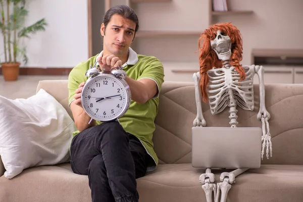 Молодой человек с женским скелетом в концепции управления временем — стоковое фото