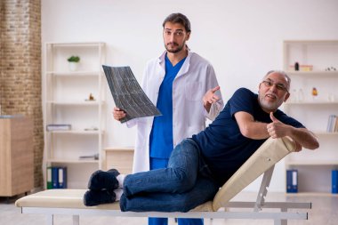 Yaşlı erkek hasta genç erkek doktor radyolojisti ziyaret ediyor.