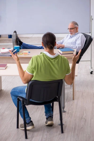 Oude mannelijke leraar en jonge mannelijke student in de klas — Stockfoto