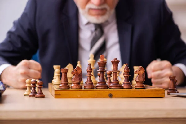 Старий чоловік, який грає в шахи на робочому місці — стокове фото