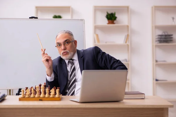 Viejo empleado jugando ajedrez en el lugar de trabajo — Foto de Stock