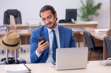 Genç erkek çalışan ofiste geziye hazırlanıyor.