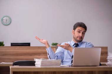 Genç bir erkek çalışan ve ofiste çok fazla iş var.