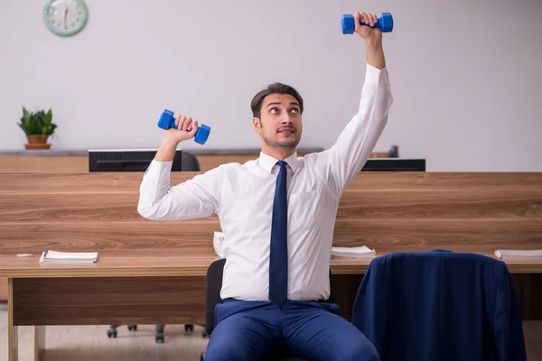 Jovem empresário empregado fazendo exercícios esportivos no local de trabalho — Fotografia de Stock