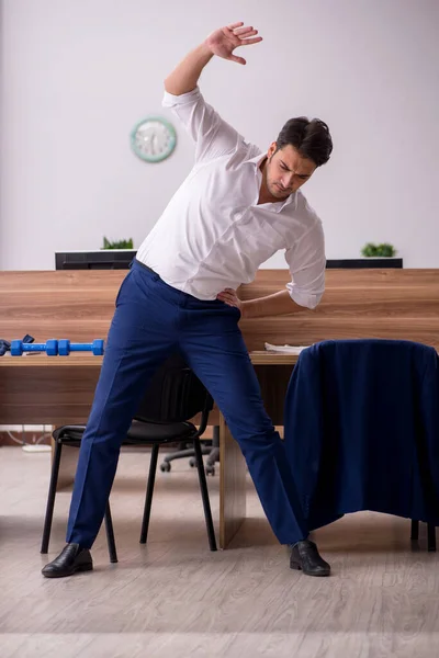 Young businessman employee doing sport exercises at workplace — Stock Photo, Image