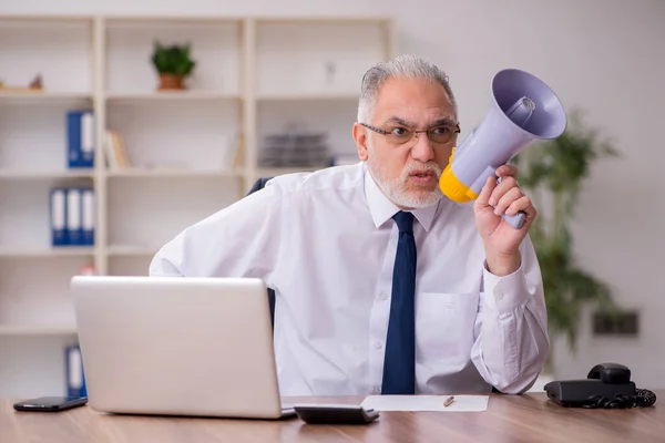 Viejo empleado sosteniendo megáfono en el lugar de trabajo —  Fotos de Stock