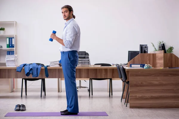 Jonge mannelijke werknemer doet sport oefeningen tijdens de pauze — Stockfoto
