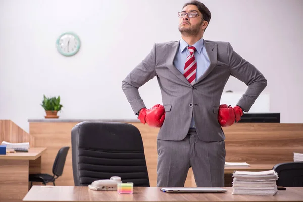 Junge männliche Angestellte trägt am Arbeitsplatz Boxhandschuhe — Stockfoto