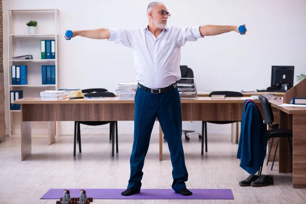 Oude zakenman werknemer doet sport oefeningen in het kantoor — Stockfoto