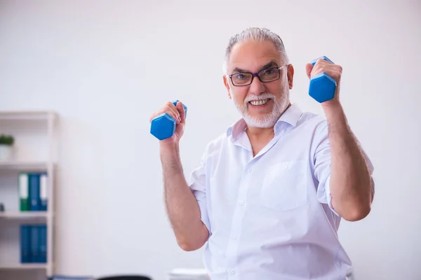 Old businessman employee doing sport exercises in the office — Stock Photo, Image