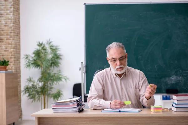Old male teacher sitting in the classroom — Stock Photo, Image