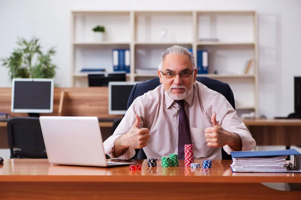 Old male employee in gambling concept at workplace — Stock Photo, Image