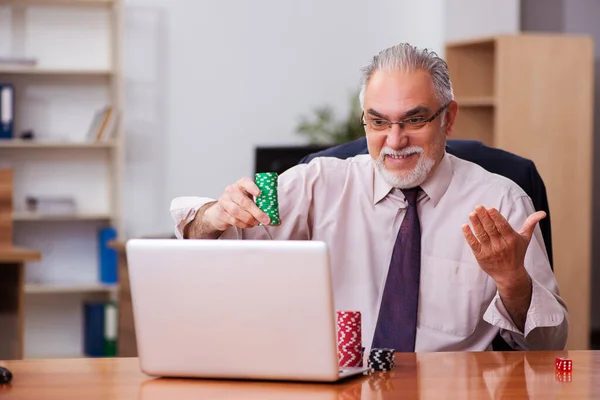 Oude mannelijke werknemer in het gokconcept op de werkplek — Stockfoto